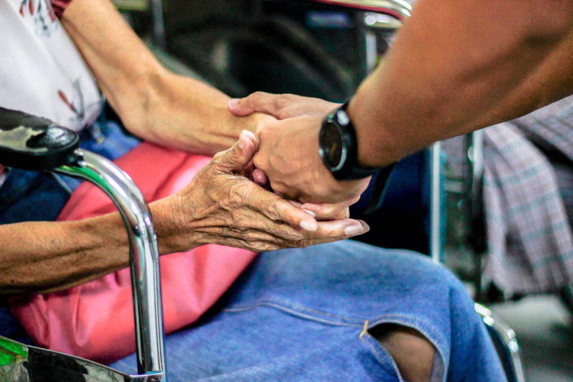 a man stood holding the hands of a woman sat in a chair