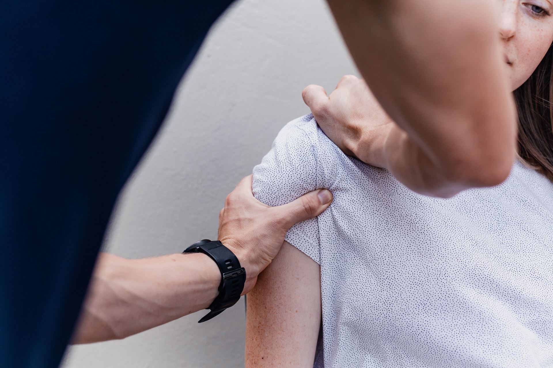 a physiotherapist with their hands on a patient's shoulder