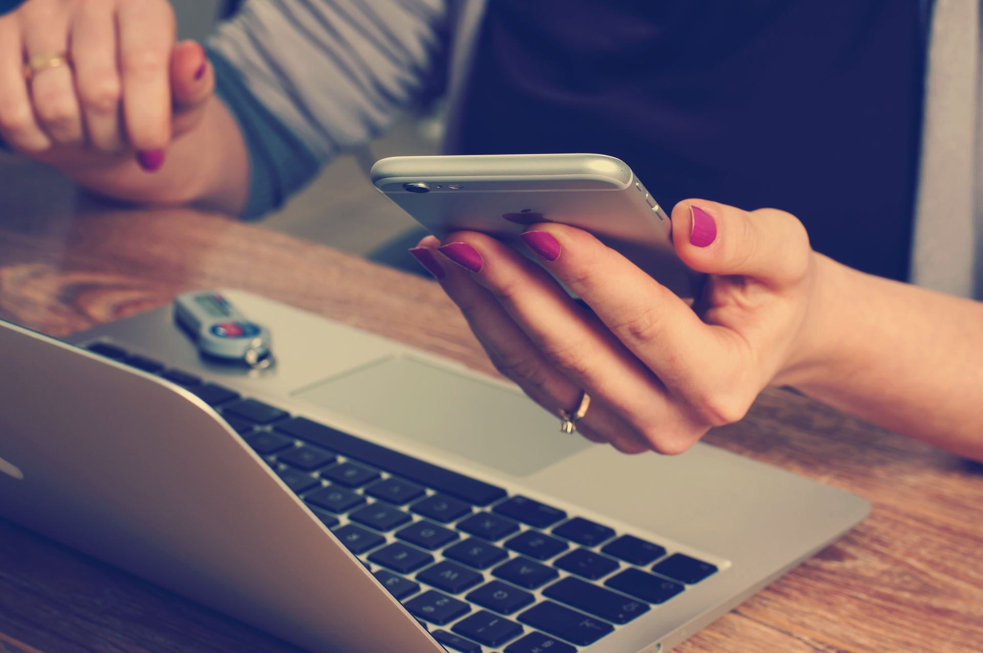 a woman holding a mobile phone, a laptop computer before her