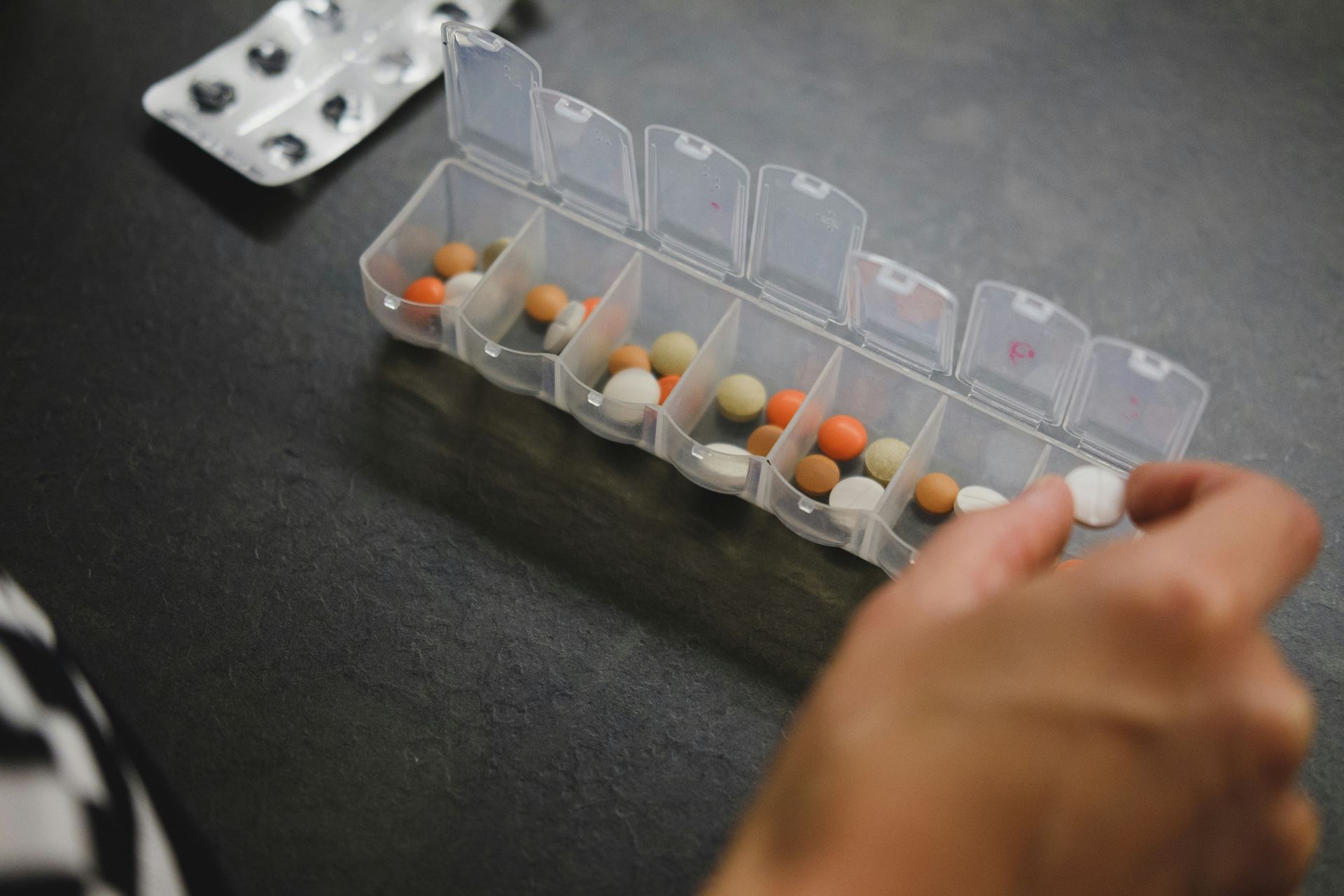 a person putting medication into a daily pill box